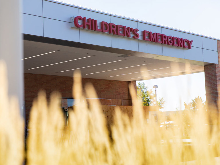 Close-up view of a ‘Children’s Emergency’ sign above a hospital entrance canopy.