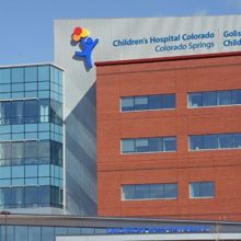 An exterior of modern hospital building that includes a mock up showing its new name: Children's Hospital Colorado, Golisano Children's Hospital, Colorado Springs.
