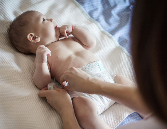 Baby boy having his diaper changed on a blanket.