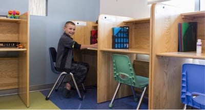 Managing Your Child’s Medical Illness at School A boy sits in a chair at a desk partition.