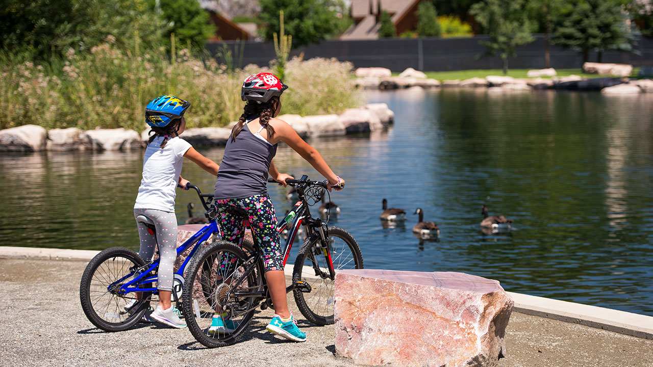 Two girls on bikes at the pond.