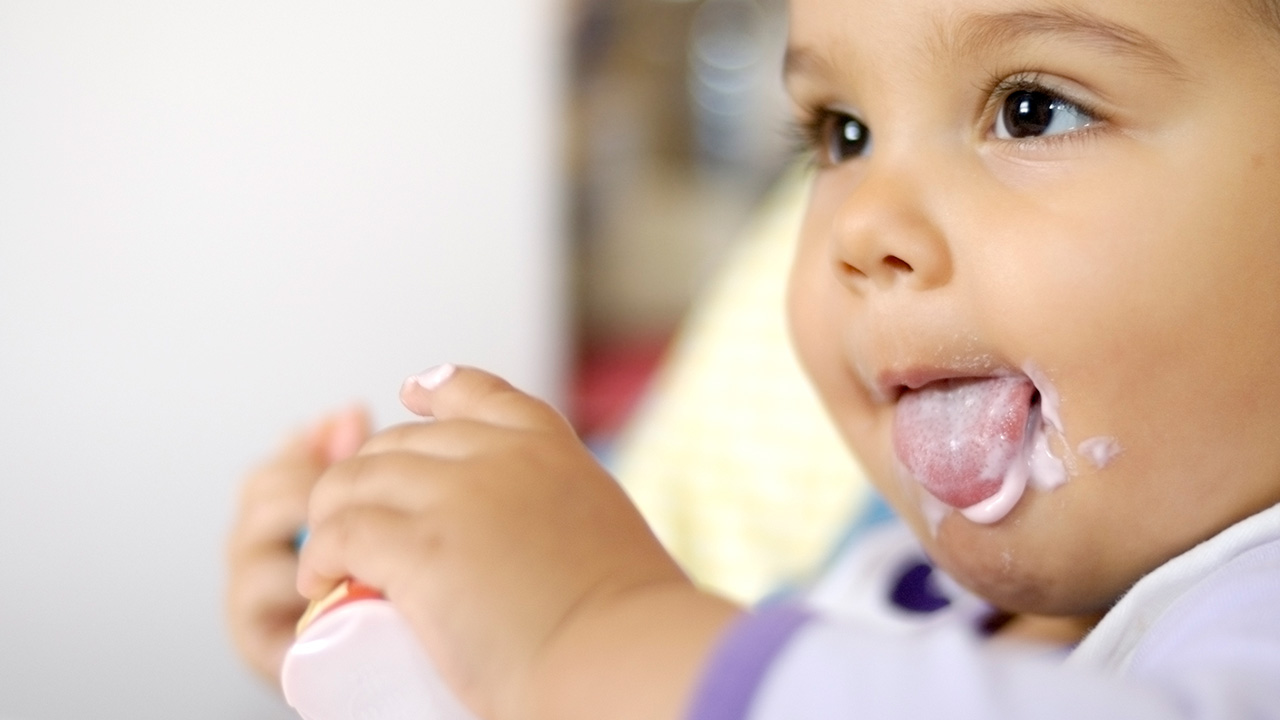 A close-up of a baby eating liquid probiotics.