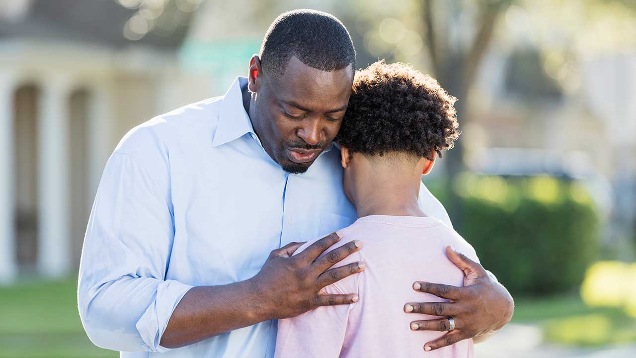A dad embraces his teenage son.