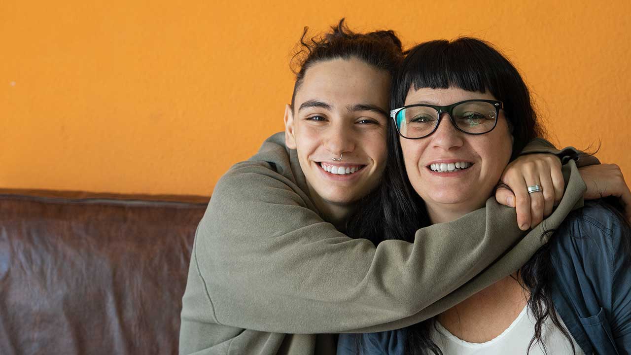 A teen hugs his mother