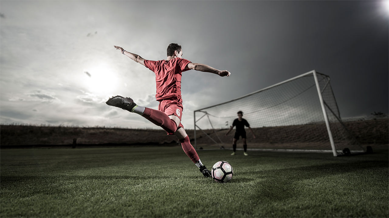 A soccer player starts to kick a ball toward the goal.