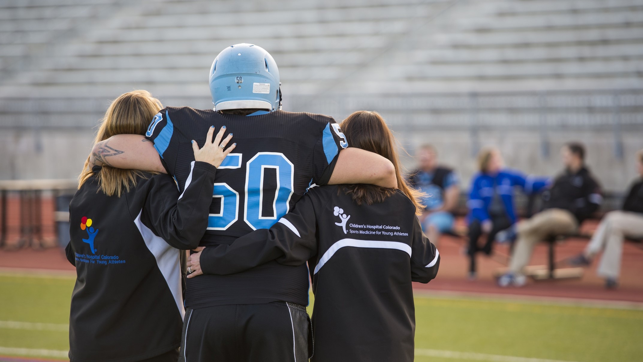 A football player gets escorted off the field by two athletic trainers.