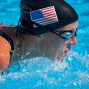 An athlete swims in a pool wearing a swimcap and goggles.