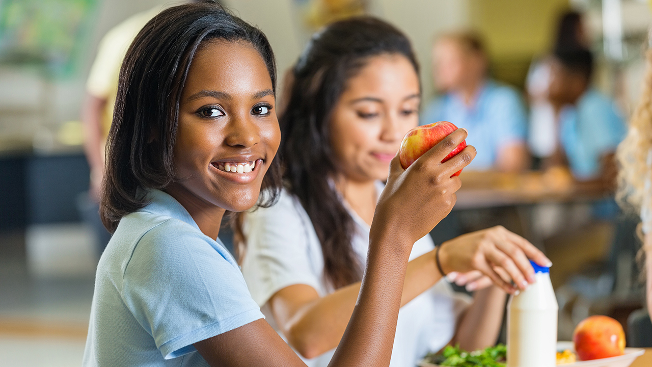 Girl holding an apple and smiling