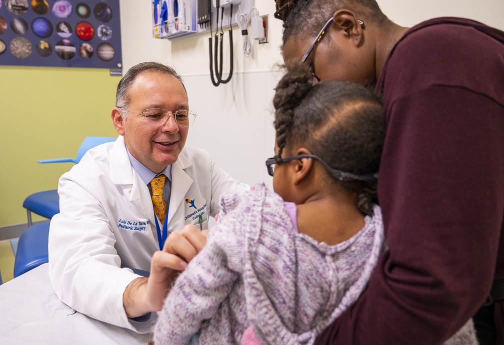 Lead study author and pediatric colorectal surgeon Luis De La Torre-Mondragon, MD, examines a young girl while her mother holds her. 