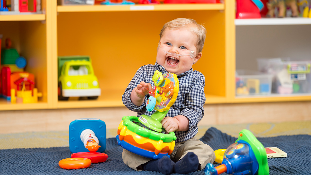Baby with oxygen tube playing with toys