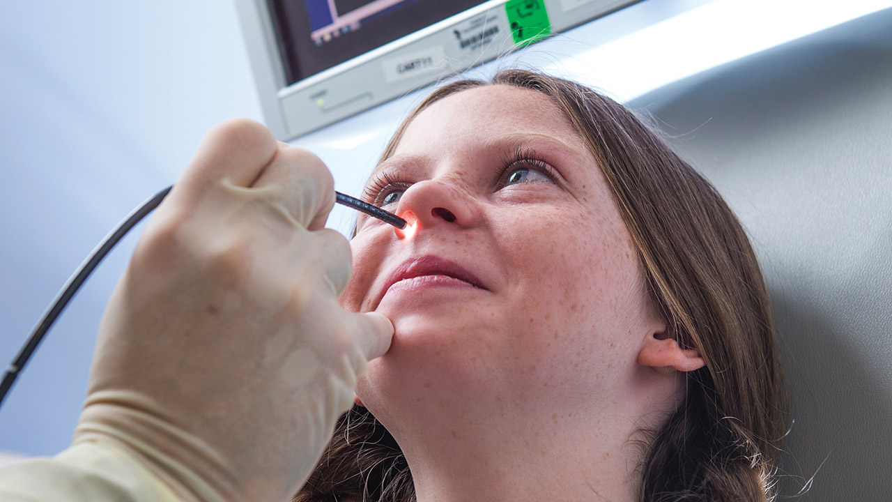 A doctor performs a nasal endoscopy procedure on a girl.