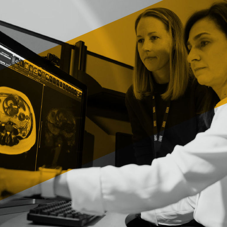Two providers review an MRI scan on a computer screen together.