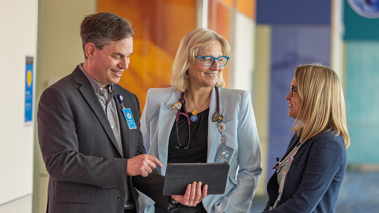 Three researchers in the Breathing Institute talk to each other and look at information on a tablet.