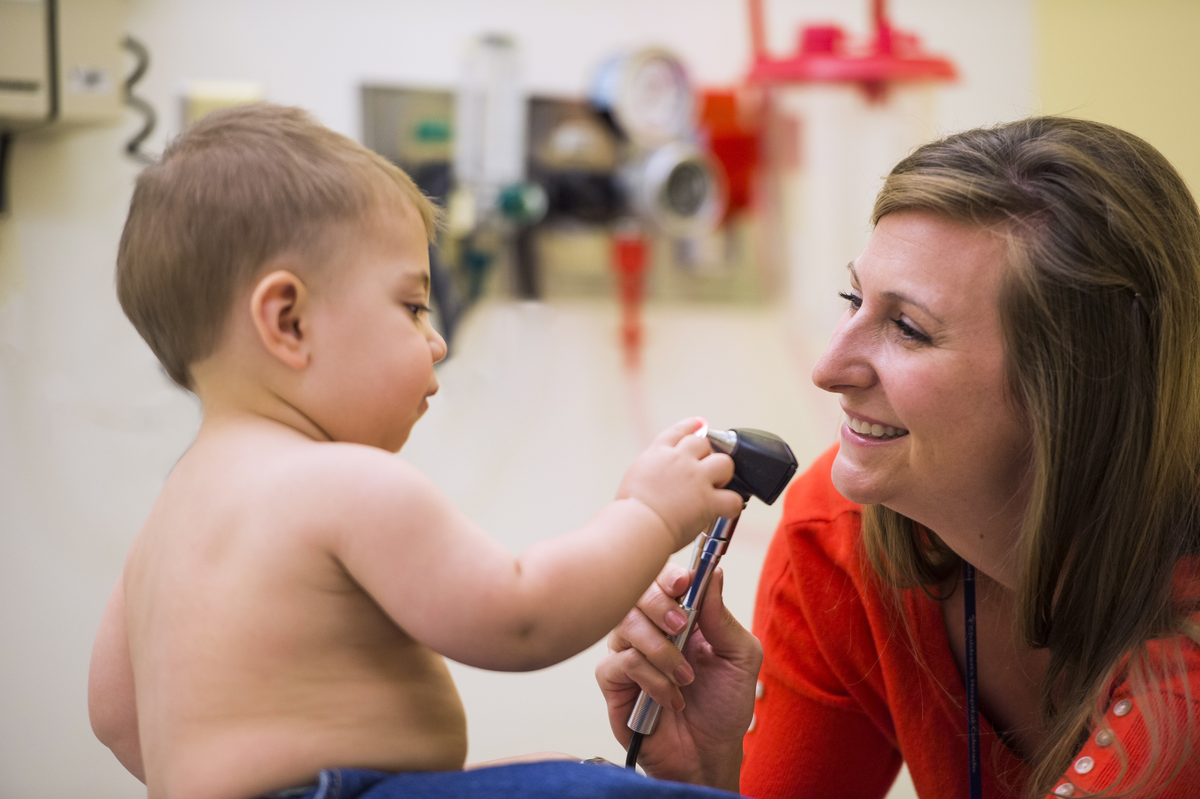 A baby plays with an otoscope.