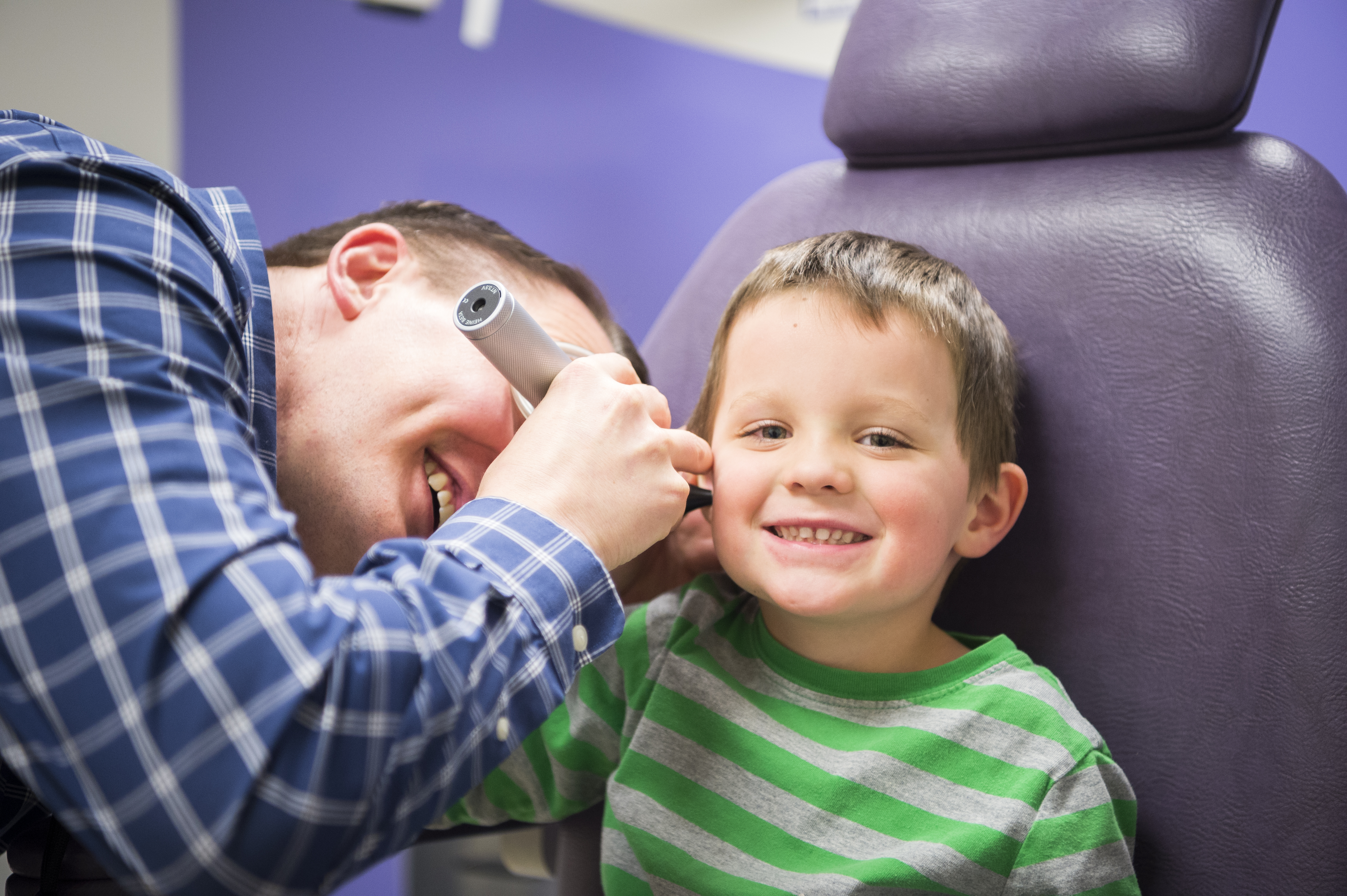 An otolaryngologist examines a young boy with an otoscope.